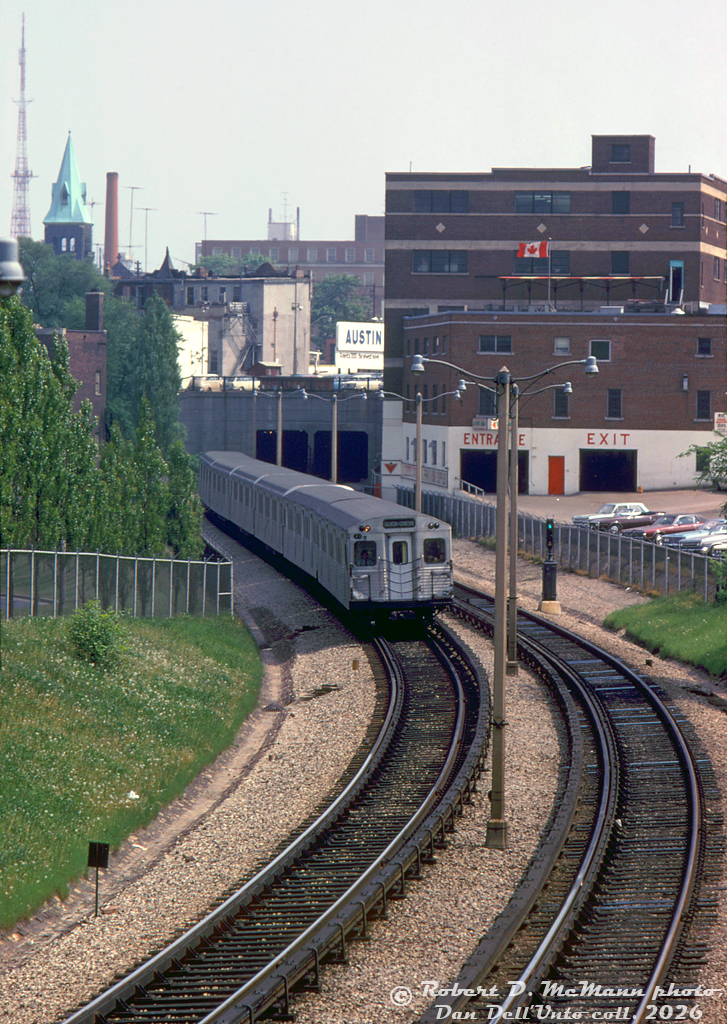 A northbound TTC Yonge line train, lead by two MLW M1 subway cars and four HSC H1 cars, heads north out of the Ellis Portal on the approach to Rosedale Subway Station. The consist is passing the back of the old Canadian Tire store along Yonge Street at Davenport,their Toronto flagship store originally constructed in 1935 and still in business today (there are proposals to redevelop the store site into high-rises, while retaining the historic front facade and a retail store somewhere inside).

Robert D. McMann photo, Dan Dell'Unto collection slide.