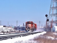 <br>
<br>
  Approach the Leaside crossover,
<br>
<br>
  White Flags denote CP Rail 5737 Extra West,
<br>
<br>
  The Phone Box at left is for the CN Leaside Branch lead (ex CNoR)    
<br>
<br>
    CNR retained the CNoR  north track rights on the CPR Belleville Sub from Donlands mile 204.6 to near the  Wickstead Ave level crossing mile 205.44 (junction service track to the  CN Leaside branch), 
<br>
<br>
for CN crews 'Movements between Donlands and Wickstead Ave will be governed by CP Rail time table' 
<br>
<br>
The signal on that gantry to the left of 5737's cab protects CP Rail  eastbound movements for the service track switch (points facing east)  connecting to the CP Rail north main track.
<br>
<br>
CP Rail 5737 is west of the Wickstead level crossing, March 2, 1980 Kodachrome by S.Danko.
<br>
<br>
More
<br>
<br>
<a href="http://www.railpictures.ca/?attachment_id= 58482">  Big M's  </a>
<br>
<br>
sdfourty