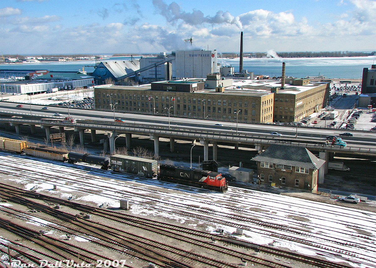 Going, downtown! A short CN train #333 with SD75I 5750 in the lead heads through the Union Station Rail Corridor in downtown Toronto on clear sunny winter afternoon, taking the "High Line" bypass tracks past the TTR's Scott Street interlocking tower on the approach to Union Station nearby. It's on the heels of CN local freight #549 with 4729 and 4139 that just passed by minutes before.

Trains #333/332 and #435 (plus a local or two) were the usual CN freights that were routed south past Union Station via the Bala/Oakville Subs, a practice that CN largely did away with years ago (probably with some pressure applied in the right places from GO/Metrolinx due to operational delays and such).In the background, much has changed: on the other side of the Gardiner Expressway is the main LCBO warehouse and headquarters (since redeveloped), Tate & Lyle aka Redpath Sugar after the takeover (still there, but no rail service). In the distance on the left are some of the Toronto Port Authority's warehouses and loading docks, and spanning much of the background are the Toronto Islands. That terminal warehouse building on the upper left near the Loblaws has since been demolished for Sugar Beach and Corus Quay. A keen eye will pick out the TTC fishbowl bus laying over on the route 6 Bay, and a GO D4500 coach laying over near Lake Ontario between runs.