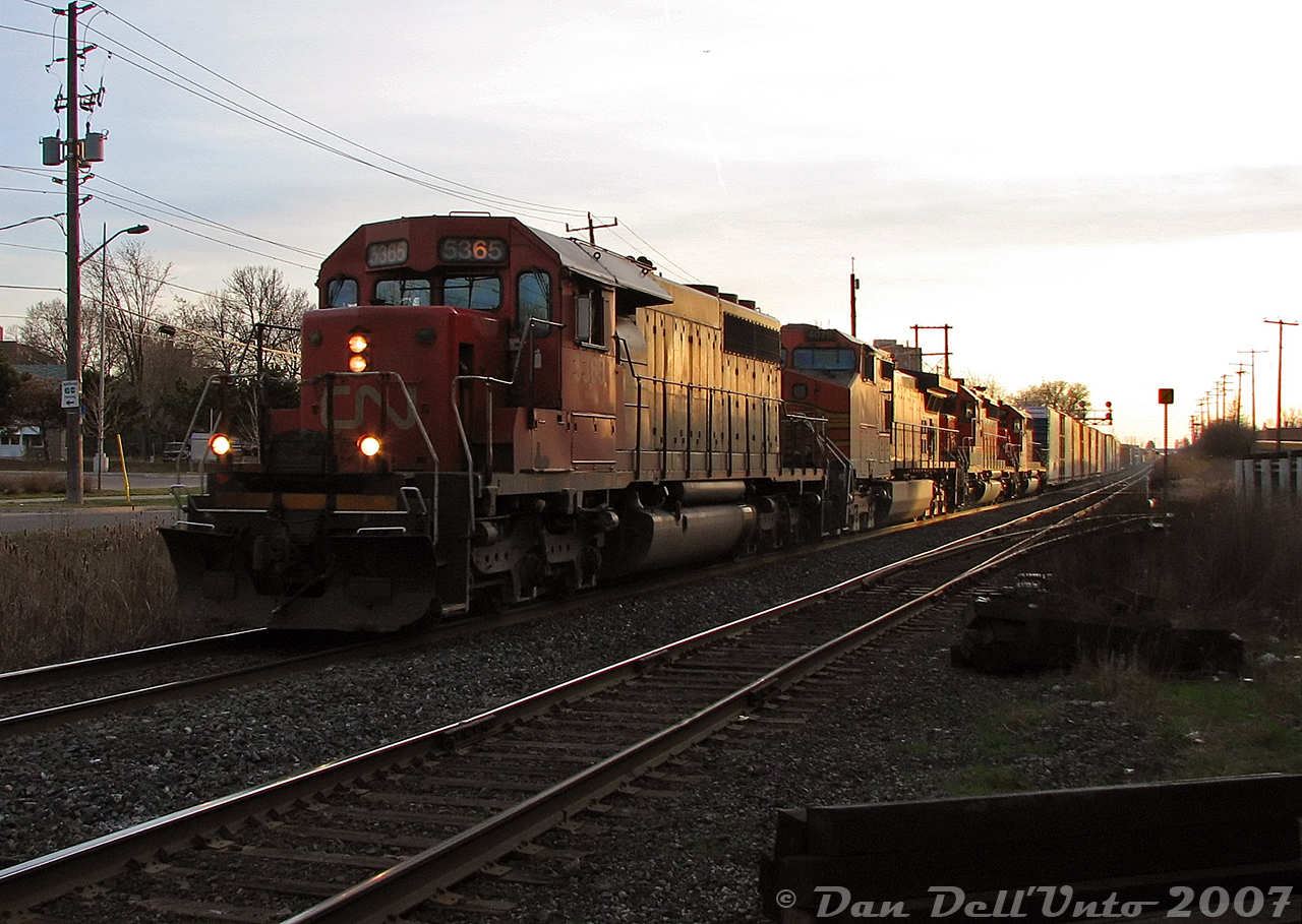 Rollin' the 40's into Brampton, elephant-style.Back in the "Foreign Power in Ontario" (FPON) era of the 2000's, a lot of good stuff from the US showed up on CN as run-through power, but by this time most had a CN leader tacked on the head-end (due to union microwave requirements on leaders, IIRC). Sometimes it rolled through overnight, or in this case, at last light: an Extra 392 slams the CN-OBRY diamond as it eases downgrade into downtown Brampton, about to cross Mill Street on its trip to MacMillan Yard. CN SD40-2 5365 leads BNSF C44-9W 4079, BNSF SD40-2 6800 (with a massive 123" snoot nose) and IC SD40-2 6119 (CN-painted). Despite the GE, the three SD40-2's all elephant style was a nice catch (the lead '40 was originally built for Missouri Pacific, the BNSF for Santa Fe, and the IC for Burlington Northern).Also neat in this image is the old CN-CP Brampton interchange track switch and dwarf signal still in place on the north track. Long disused, they would finally be removed later that year in the Summer of 2007 during diamond signal upgrades by CN.