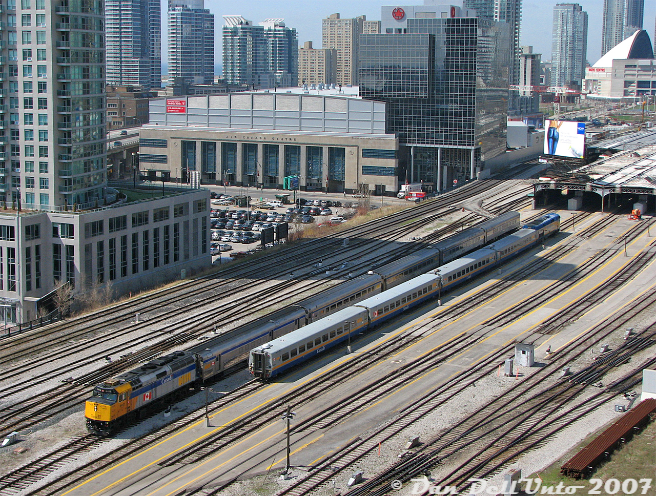 Back on Dan's model train layout of Union Station, circa 2007, we have VIA Rail train #60 departing eastbound from track 10 with a Rapido Trains DCC/Sound F40PH-2D 6412 and 5 stainless steel kitbashed Walthers HEP cars, waiting while VIA #53 with Athearn Genesis P42DC 918 arrives with four Rapido LRC cars in tow (the ones from the first run that roll like iron sleds) into track 9 under the train shed. As you can see, we maxed out our credit card buying all that Atlas flextrack and many, many PECO double throw slip switches (too many), and ballasting it all with Woodland Scenics products took forever.

There's some scratchbuilt buildings in the background including part of the Air Canada Centre (partially kitbashed from an old Bachmann post office kit), and our 3D-printed Skydome complete with working lights and dome action, fully open today for the miniature Blue Jays to win the Stanley Cup of Baseball. We got a good deal on Walthers Cornerstone cookie-cutter condos that were on deep discount at George's Trains when they closed their Mount Pleasant store (RIP 510 Mount Pleasant), so pretended we were a real estate developer and threw them in wherever there was some bare layout showing, blocking out Lake Ontario so we didn't have to scenic it (still need to add more condos in the future, might remove some other buildings from the layout here to make space). Our parking lot was populated with a selection of late-model HO-scale Brenka and Walthers cars for the afternoon (good spot for a future condo, hmmmm). That old brown building to the left of the ACC is the former OPP headquarters, that I think I picked up at a swap-meet for 5 bucks off a used table (might replace that with condos too). Our layout lighting however, has the unfortunate effect of always being at the wrong angle for shooting from this side of the aisle. Oh, that billboard ad was cut out from the Sears catalogue and glued on a used Walthers billboard found at a Brampton train show, it previously had an ad for some company called Nortel.

Future updates include some Bachmann VIA Siemens Charger trainsets and a Northlander, many more condos, a little train museum somewhere nearby for the relics and inoperable models, yet more condos, and I may have to cut a giant hole in my train shed to put a large plexiglass ice cube on top. We won't run freights down here anymore since someone recently derailed their CN #435 over at Mimico and no GO trains could get out of the staging yard, messing up our entire operating session that one afternoon...