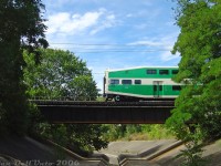 GO Transit cab car 210 punches out of the foliage above the Etobicoke Creek, heading west on train #281 (Union-Bramalea with F59 563 on the rear) on the final push to downtown Brampton over the single track section of the Halton Sub between Peel and Brampton East. We had just made it over here from the Dixie Cup Spur to shoot <a href=http://www.railpictures.ca/?attachment_id=27631><b>CN #559</b></a> (finished from switching Georgia-Pacific) backing past and slipping into the clear at Peel about 10 minutes before. Shooting anything off the pedestrian bridge here, you had to keep your ears peeled and know when something was coming in order to time the shot correctly, since there was no visibility down either side of the line. The regular GO trains with a schedule committed to memory made things a bit easier.<br><br>For some very not smart reason lost to time, the old town of Brampton (downtown) was built OVER the Etobicoke Creek, with the original alignment following Main Street winding south underneath some of the buildings downtown. This caused many seasonal flooding issues, including very significant flooding of the entire downtown area in March 1948 (see olde-timey documentary <a href=https://www.youtube.com/watch?v=PBO7cbHj9L0><b>here</b></a>, 10:32 shows this exact spot). After this, Brampton had enough of decades of mother nature casually trying flood it out of existence. A new concrete diversion channel was built to the east to divert the creek alignment out of and around the downtown area, running from Vodden Street to here, just south of a new CN bridge. At the time of this photo, the bridge was part of the <a href=http://www.railpictures.ca/?attachment_id=12490><b>single-track</b></a> "gauntlet" between <a href=http://www.railpictures.ca/?attachment_id=9714><b>Brampton East</b></a> and <a href=http://www.railpictures.ca/?attachment_id=2143><b>Peel</b></a>, but CN would soon add another span here in 2006-2007 on the north side in order to double-track the line all the way through.