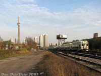 You've seen the view from <a href=https://www.railpictures.ca/?attachment_id=59189><b>aboard the train</b></a>, now here's the view from on the ground: Milton-line GO train #153 lead by cab car 236 (with F59PH 556 pushing leisurely on the rear) rocks through the crossovers at 30mph as it approaches the Strachan Avenue grade crossing in Liberty Village, about to exit the western USRC limits and enter CP's Galt Sub.<br><br>Wandering into the Strachan Avenue area of Liberty Village/Parkdale in the late 2000's felt like entering a de-industrialized wasteland of hollowed-out post-industrial decay. A large <a hef=http://www.railpictures.ca/?attachment_id=15195><b>multi-track grade crossing</b></a> one could just wander into, set amid an area with old warehouses and factories waiting to be torn down and redeveloped, including such welcoming landmarks as the Wellington Destructor garbage incinerator (note brown building with smokestack on left), the <a href=http://www.railpictures.ca/?attachment_id=31854><b>Toronto Abbatoir</b></a> slaughterhouse next to it (still in operation at the time), the old <a href=http://www.railpictures.ca/?attachment_id=55580><b>Canadian Patent Scaffolding building</b></a> (occupied by some used office furniture business), the old police garage(?) on Ordnance St. all closed up, and the John B. Smith building (out of frame on the left) complete with that mismatched wall of old doors. All the former <a href=http://www.railpictures.ca/?attachment_id=35550><b>freight yards and sidings</b></a> had been pulled up long ago. Modern progress loomed in the background as the wall of downtown condos encroached. Soon Liberty Village, still in the process of gentrification at the time with a number of its old buildings demolished or converted to trendy lofts, would soon start getting many new condos of its own, and sweep more of its <a href=http://www.railpictures.ca/?attachment_id=36870><b>industrial past</b></a> away.<br><br>This last vestige of easy rail access that hosted a flurry of GO and VIA activity every rush hour (multiple Bradford, Georgetown and Milton line trains, and six daily VIA corridor trains to Sarnia) would become a giant hole in the ground a few years later, with the <a href=http://www.railpictures.ca/?attachment_id=25804><b>grade separation</b></a> tunnel making it near impossible to shoot at Strachan Avenue anymore (but the <a href=http://www.railpictures.ca/?attachment_id=41837><b>nearby pedestrian bridges</b></a> offers a few possibilities from above).