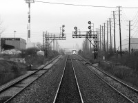 Here's a complementary view to go with <a href=http://www.railpictures.ca/?attachment_id=59625><b>Woodbine East</b></a> along the Weston Sub: CN Woodbine West, Mile 14.1 CN Weston Sub. Our view is trailing eastbound aboard GO cab car 241 on train #260 (Bramalea-Georgetown) after making our stop at Malton GO station, hidden by the approaching train. <a href=http://www.railpictures.ca/?attachment_id=34973><b>CN #577 with sister GP40-2LW units 9411-9410</b></a> is about to crest the grade on the north service track and will follow us downhill, enroute to West Toronto to interchange traffic with CP. In the distance one can see the Highway 407 overpass at Halwest, and faintly the Owens Illinois glass plant in Brampton.<br><br>The siding on the right is for the Home Depot's Malton lumber distribution facility (receiving boxcars and centre beam flatcars). The switch to the left was the old American Can Lead that lead into the Northwest Dr industrial area, serving customers in the business park that once included IGA, American Can and Kuehne & Nagel (Brenntag Canada was the last active customer before removal). Fairmont Motor Company even had a warehouse and siding at 6320 Northwest Dr. This area of Malton also used to be home to a variety of aircraft manufacturing facilties, including the large McDonnell-Douglas/Boeing Malton plant at Airport & Derry (of Avro Arrow fame), Orenda Engines, and DeHavilland (now the International Centre), all of which used to receive rail service from various sidings off the Weston Sub.<br><br>The tracks here have since been upgraded, and the signal bridges replaced. Most of the old sidings and spurs have been pulled up, with the only remaining customer being Home Depot.
