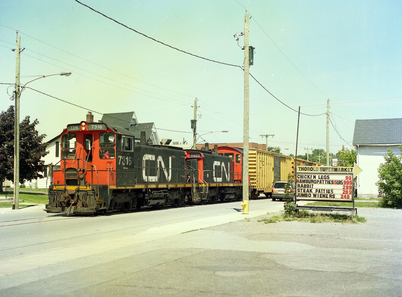 For those who have followed Railpictures.ca for a number of years will recall I posted a couple of images of the last run to Gallagher Paper (recyclers) on Pine St in Thorold.  The company had gone bankrupt and CN sent a couple of switchers to retrieve the last rolling stock at the plant, which amounted to 3 boxcars. The move is seen leaving Pine St spur for the very last time, as it rolls past the Thorold Supermarket; a nice 'prop' for identification. It wasn't easy pacing a train even though it was only doing about 10 MPH.
CN gave up this and adjacent track in the area to the fledgling PCHR (Port Colborne Harbour Rwy) soon after, but with no business left on the Pine St spur, I don't believe they ever ran anything down this stretch of track.
I believe the Pine St line has been paved over or taken up in the past few years. Haven't been along there to check.  Anyone?