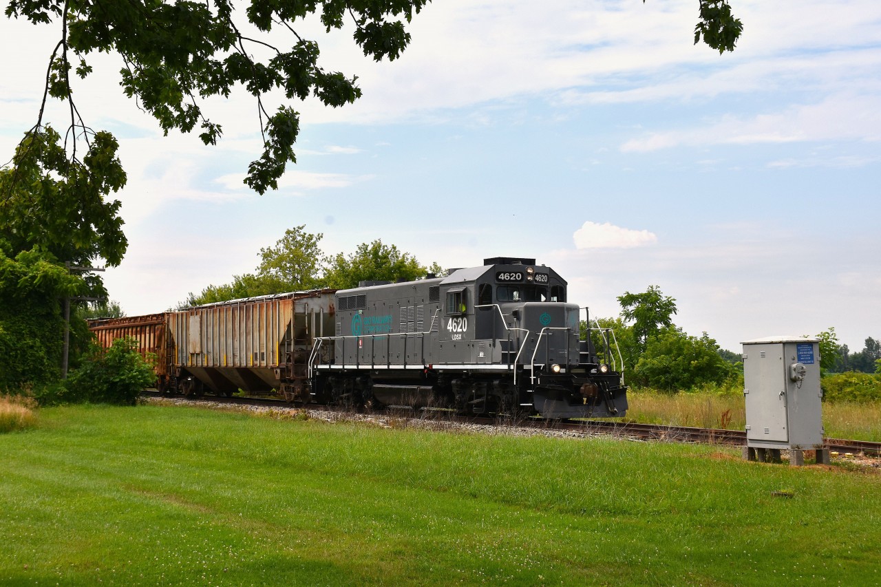 When wandering out to St. Thomas (for lunch) and back, I usually do not see much of anything. It was a surprise to hear a horn in the distance as I left the restaurant, and got ahead of this eastbound train at New Sarum, as it came up to Belmont Rd (Hwy 74). The former GTW GP9R is now in GIO dress, as I suppose most fans around Southern Ontario know.
The line is the St. Thomas, Alymer and Tillsonburg Rwy, a division of GIO. Image taken at mile 113.56, Cayuga Spur. (so reads the info on the silver box!)