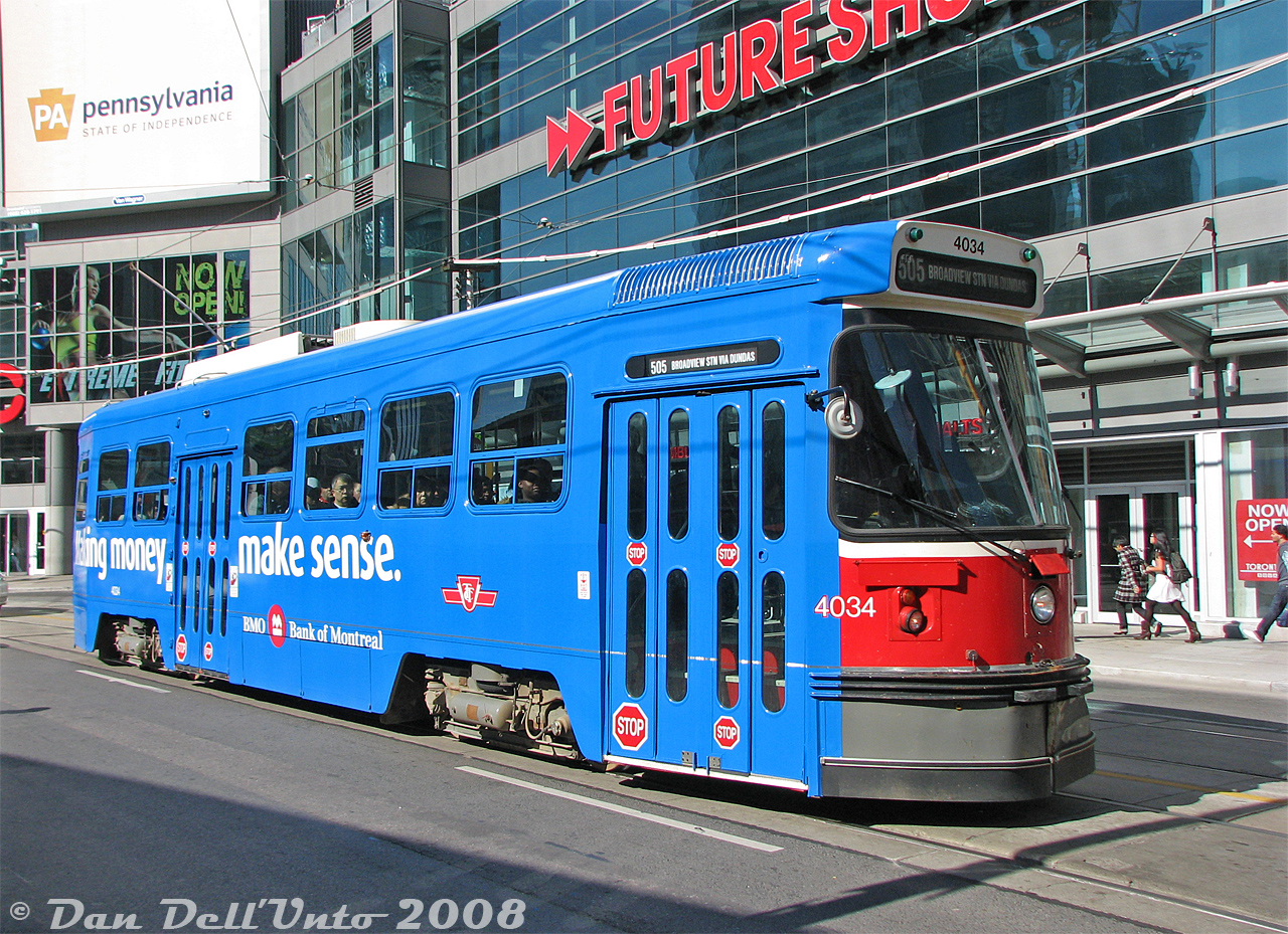 Not your typical red Toronto streetcar: TTC CLRV 4034 sports a bright blue wrap for the Bank of Montreal (BMO) paused heading eastbound on Dundas at Victoria in front of the relatively new 10 Dundas East building (now called The Tenor building). The Future Shop located here, while it lasted, was handy to stop by for electronic odds and ends, but its proximity to the nearby Best Buy in the Ted Rogers School of Management building (Dundas & Bay) eventually doomed it.