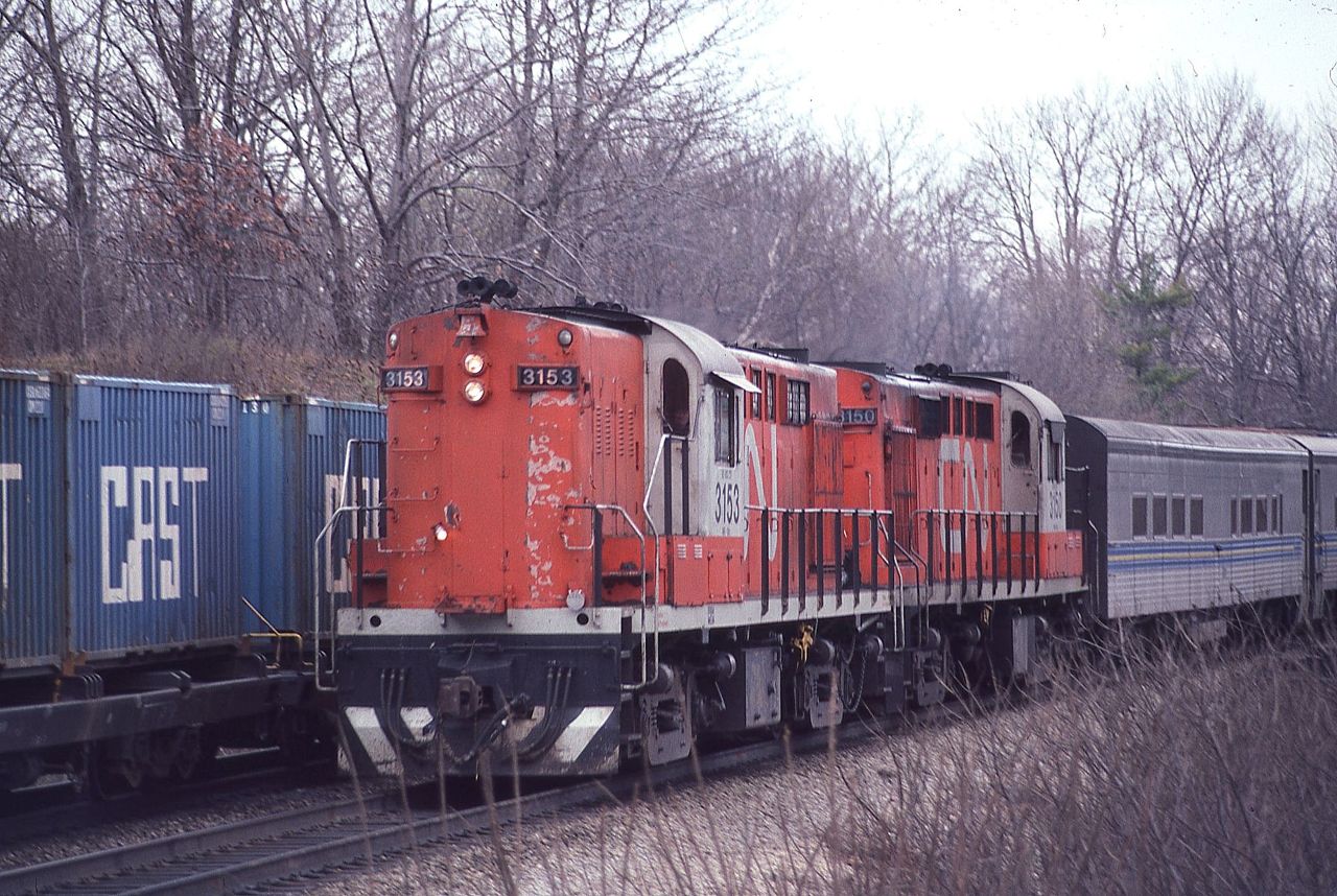 A westbound CN Tempo train for Windsor, Ontario creeps by a stopped train with some CAST containers at Bayview Junction on April 12, 1981.