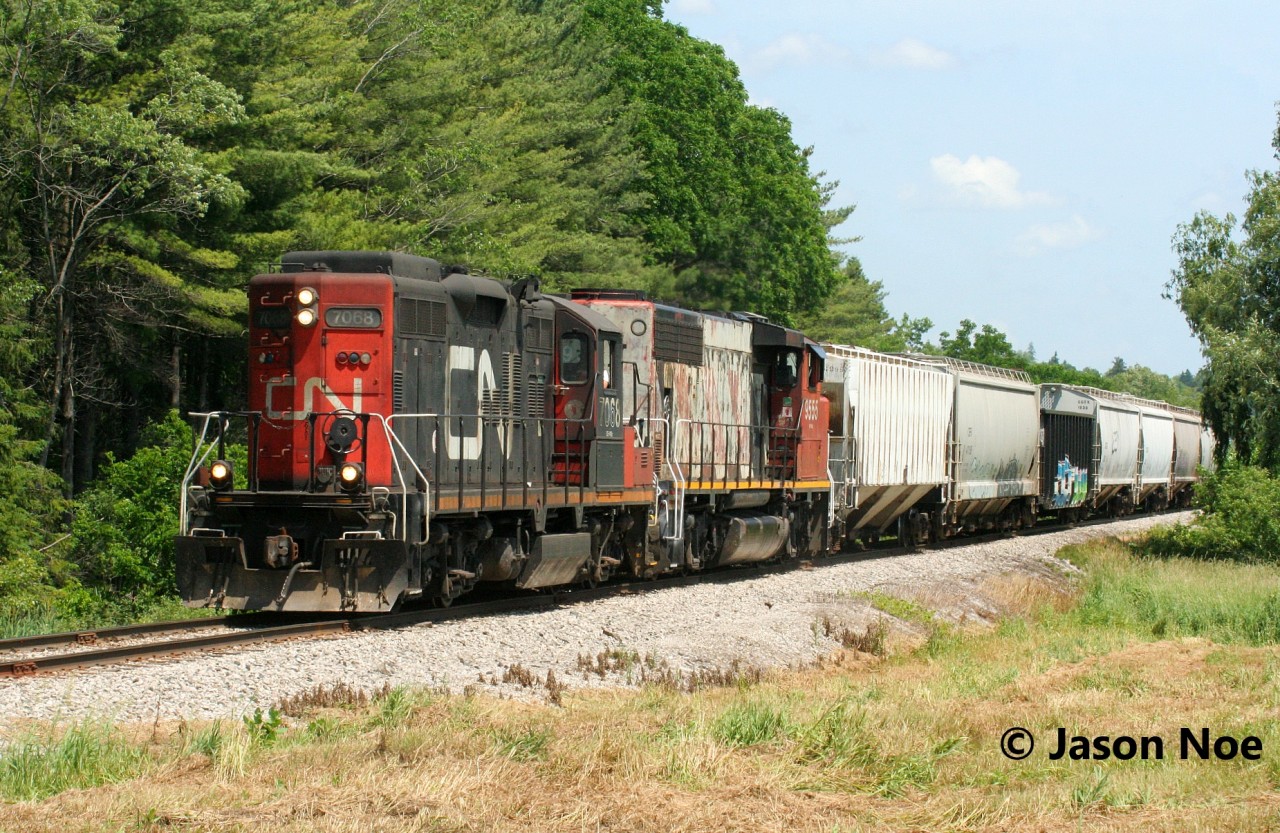 CN L568 is viewed heading west to Stratford with GP9RM 7068 and GP40-2L(W) 9555 passing Mile 68 on the Guelph Subdivision, just west of Kitchener.