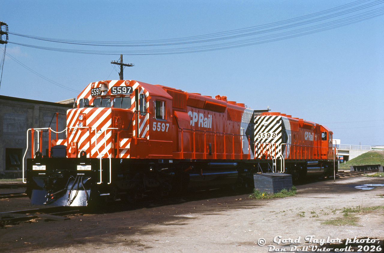 You can just smell the new paint! Brand new CP Rail SD40-2 units 5597 and 5598 sit in fresh spotless red, white and black "Action Red" paint at CP's Quebec Street Shops, newly outshopped from the nearby GMD London plant. Both feature the then-current large multimark and 5" full front cab and end striping. Note CP/Canadian-specific details including vertical steps and profiled handrails, nose-mounted headlight on early 81' short hood, numberboard-mounted brass bell, single class lights, nose brakewheel, CP-style rock pilot plow, Nathan Airchime K3LR2 horn, end pilot lift rings (no ditch lights for a few more years), and single rear headlight with no end numberboards. Red marking and chain keepers on the end MU hoses are a nice touch. Also of local interest is the roundhouse turntable near the Quebec Street overpass.Both units were part of CP's second order for EMD/GMD's new SD40-2 model: GMD order C-349 for CP units 5589-5628, DRF-30h class, built May-July 1972. Both were outshopped at the same time, and (as per the Dean & Hanna CP book) officially added to the CP roster on May 19th 1972. 5598 was retired after an accident on the Ignace Sub in March 1979, while 5597 was retired in 2004 and sold to NRE (then resold to the Chicago, Fort Wayne & Eastern RR).Gord Taylor photo, Dan Dell'Unto collection slide.