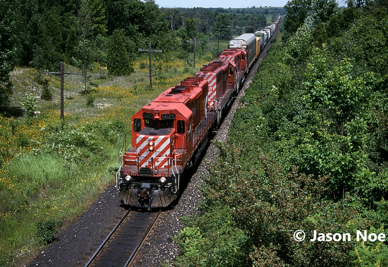 During a hot summer afternoon, a westbound CP train is viewed approaching the east siding switch at Puslinch, Ontario on the Galt Subdivision with SD40-2’s 5629, 5578 and SD40 5536.