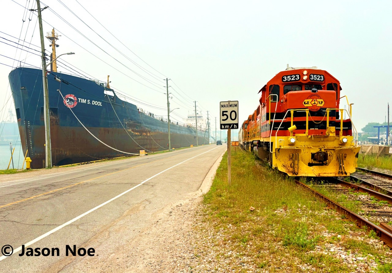 Goderich-Exeter Railway train 581 is preparing to depart the Port of Goderich, Ontario with a cut of loaded salt hoppers as the MV Tim S. Dool lake freighter waits in the harbor. 581 was powered by GEXR GP38-2 3523 and RLHH GP38-2 2117.