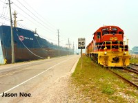 Goderich-Exeter Railway train 581 is preparing to depart the Port of Goderich, Ontario with a cut of loaded salt hoppers as the MV Tim S. Dool lake freighter waits in the harbor. 581 was powered by GEXR GP38-2 3523 and RLHH GP38-2 2117. 
