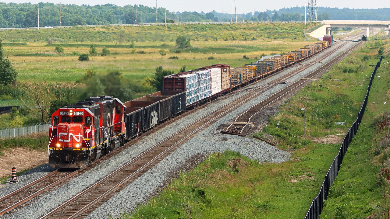 L551 with the GTW 6425 CN 4936 heading eastbound toward Milton with a good size train today. L551 is operating on the newly constructed south track between Mile 38.9 and Derry Mile 36.9, having just passed over the future parallel right hand crossovers which will form part of a new Controlled Location. The former main track, now the north track is partially new construction before being cut into the existing track. The former main track can be seen off to the right, portions of which will eventually form one of two yard leads for what will become the east entrance/exit to the Milton Logistic Hub. The former Controlled Location Ash, Mile 38.8 has been removed.