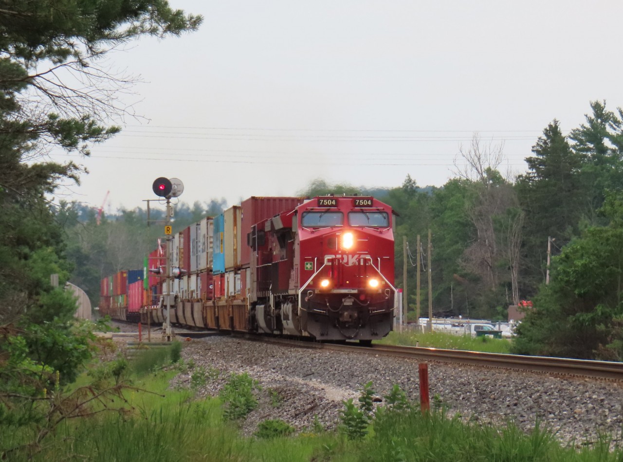 A northbound intermodal crosses Highway 26. CP recently rebuilt this road crossing. For about a week there was a nasty bump in the road as the rails were a couple of inches higher with a short ramp up. The approaches have been re-paved so things are smoother now.