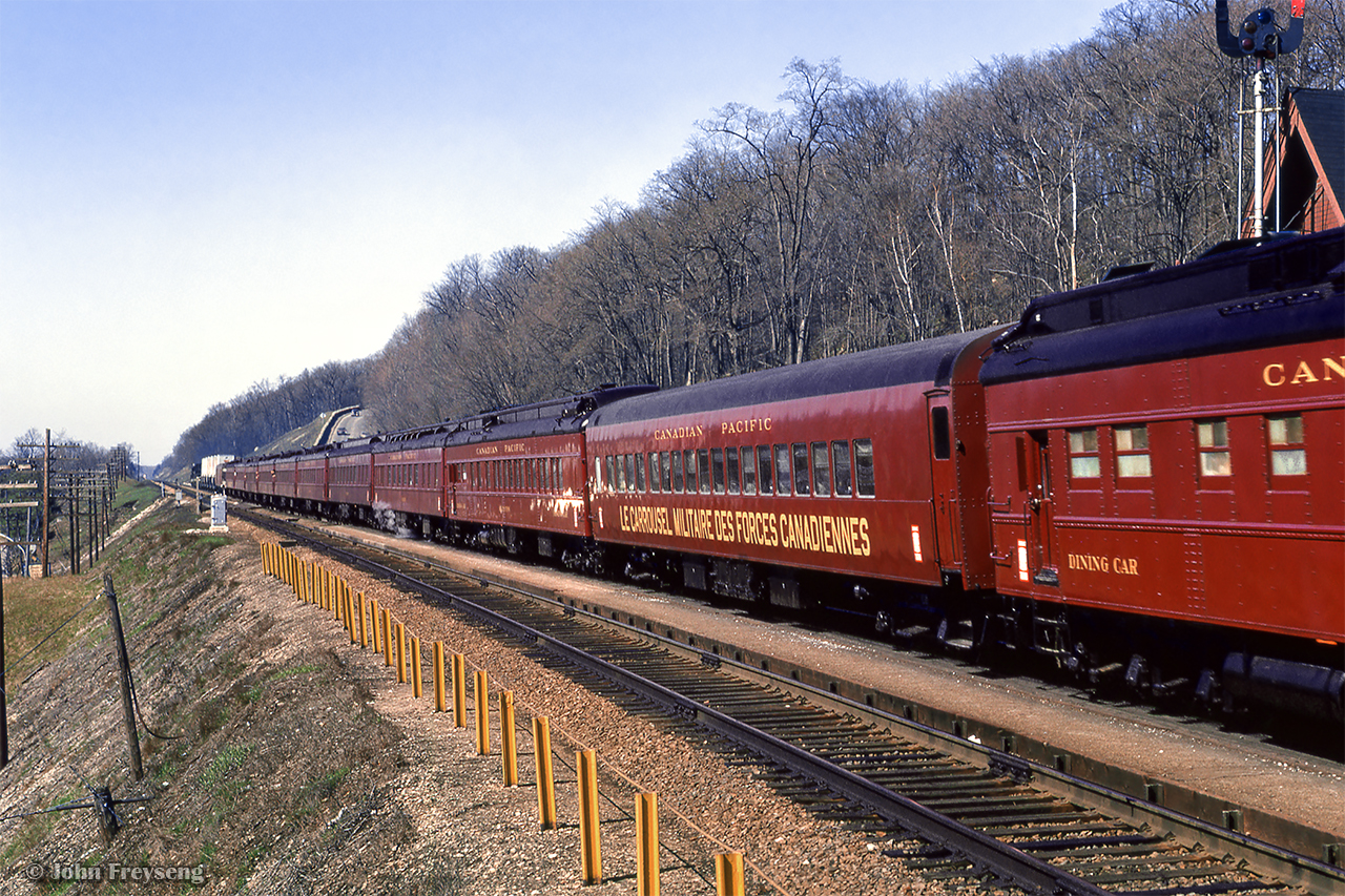Touring the nation as part of the 1967 centennial celebrations, one of the two trains carrying the Canadian Armed Forces Military Tattoo climbs the grade at Dundas, bound for an evening performance in Sarnia. The tattoo was designed to operate as three parts, with part 1 being the initial tours of the two trains from late March through mid May, performing arena shows with 450 performers. One consist was made up of CN equipment, known as 'train A,' and carried the 'blue' group of performers, while the other was made up of CP equipment, aka 'train B,' carrying the 'red' group of performers. In late May, both groups combined, and additional performers added, bringing the total to about 1700 for the next stage of shows; stadium performances from late May through August. The final part of the tattoo would be smaller shows beginning in late summer, and wrapping up in mid October. Further reading can be found on Keith Allan Wilson's Tattoo 1967 website, as well as the itinerary of events for the year.  More photos to come, and more details on this can be found in Tom Henry's article in the April 1967 UCRS newsletter.

Approaching the scene

Scan and editing by Jacob Patterson.