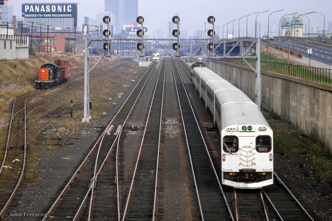 Cab car GO 9851 trails on an eastbound train for Pickering crossing over from track 3 to 4 at Dufferin approaching Exhibition GO, while a westbound pair of self-propelled cars can be seen on track 1 making their station stop.
Scan and editing by Jacob Patterson.