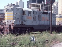 Quebec, North Shore and Labrador GP9 # 133 is seen near Toronto Union Station in July of 1982. The fabulous Royal York Hotel is seen peeking through in the background. All this area is of course changed today.