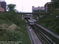 The first pair of TTC's brand-new Hawker Siddeley H1 subway cars (5336-5337, delivered to Davisville Yard <a href=http://www.railpictures.ca/?attachment_id=32616><b>earlier that month</b></a>) operate on a special official train, heading southbound in the open-cut portion of the Yonge subway line at Jackes Avenue (taken looking north from Woodlawn Avenue).<br><br>According to notes by John Bromley and Robert McMann in an old <a href=https://bzglfiles.s3.ca-central-1.amazonaws.com/u/131959/d1e3052fb729d4d460a0de984656ca1fcfa17780/original/ucrs-234-1965-jul-jps.pdf><b>UCRS issue</b></a>, this was a test train preview run of the new H1 cars with 40 transit officials aboard, run on the morning of May 30th 1965 (departing 8:30am, with the only two cars delivered to Davisville) between Davisville Station and Union Station, followed up by breakfast at CP's Royal York Hotel. The pair of new cars had previously been testing on the line, and it was expected full consists of the new H1's would be in revenue service by mid-July 1965.<br><br>This section of the Yonge subway line between St. Clair and Summerhill stations would be completely covered over in the following years, as part of development of air rights over the subway line. That high bridge for Jackies Avenue would be completely level with the new ground over the line, with nary a hint of the subway cut below except some bridge railings that were left in place. Today, a very large apartment building resides over the space in the foreground, with greenspace over other portions.<br><br><i>Robert D. McMann photo, Dan Dell'Unto collection slide.</i>