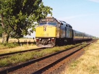Via GMD F40PH 6408 leads a westbound past the station in Gananoque, Ontario, in July of 2004. This unit later was given a Spiderman livery. A recent (2023) Google Maps view shows that the big old tree on the north (left) side of the tracks is not looking so great.