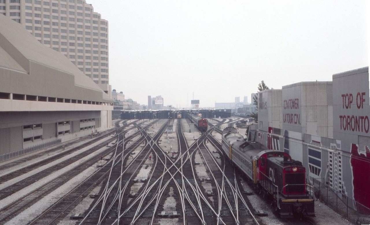 This view looks east towards the west end of Toronto Union Station in August of 1985 - what a puzzle of tracks indeed. Two of the then ubiquitous S-13 switchers are hard at work bringing passenger equipment to and from the coach yards to Union Station. Note the signs on the right for the CN Tower and the "Top of Toronto." The restaurant name was changed to the "360 Restaurant" a decade later in April of 1995. All of this area has been completely changed.