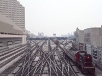 This view looks east towards the west end of Toronto Union Station in August of 1985 - what a puzzle of tracks indeed. Two of the then ubiquitous S-13 switchers are hard at work bringing passenger equipment to and from the coach yards to Union Station. Note the signs on the right for the CN Tower and the "Top of Toronto." The restaurant name was changed to the "360 Restaurant" a decade later in April of 1995. All of this area has been completely changed. 
