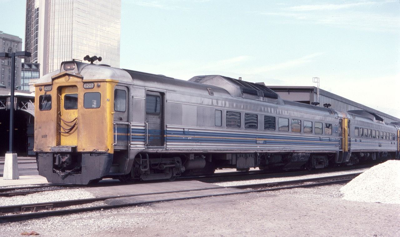 Via RDC 6207 is seen at the west end of Toronto Union Station in July of 1982. The gold-colored Royal Bank Tower is seen in the background across the street. The twin towers have real 24 karat gold in the windows, hence the gold color.