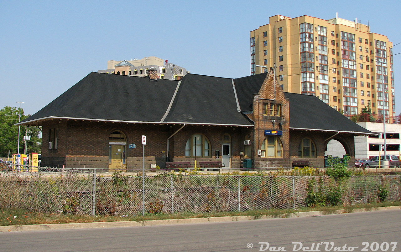 Another for the train station fans: the old GTR/CNR Brampton Station, taken from along Railroad Street looking at the platform view on a sunny afternoon. The brush wasn't as heavy that summer, affording a fairly clean shot compared to years past when the bush blocked the entire station view here. Back in 2002-2004 when I used to walk along Railroad Street from the bus terminal (the 9 Vodden was always good for a GM fishbowl ride downtown) to patronized The Little Train Shoppe nearby, the overgrowth was so bad it was hard to tell there was even a train station here, and I never bothered visiting it. But, I did note down things like the Amtrak/VIA International, and the GEXR with leased CN GP40-2LW's, even if the film camera was not at the ready.

This was the second Grand Trunk Brampton Station, built in 1907 as a replacement for the first when the fine growing farming and flower town of Brampton demanded increased train service from GTR, and a more modern station building. It has managed to stand the test of time through the GTR/CNR era (at the time of this photo, it would have been 100 years old) and now serves as the local downtown GO Transit/VIA Rail station.At one point there were plans to build an entire Ryerson University medical school in the parking lot right next to the station, in the much-toted "Brampton Innovation District", but city council eventually gave them the old Bramalea Civic Centre (much to the ire of longtime Bramalea residents, and giving up Bramalea's newly renovated public library in the process), and the station area was spared that indignity, and looks about the same today with an extra platform shelter or two blocking it in the foreground.

A 1981 view by Bill Thomson: http://www.railpictures.ca/?attachment_id=22176