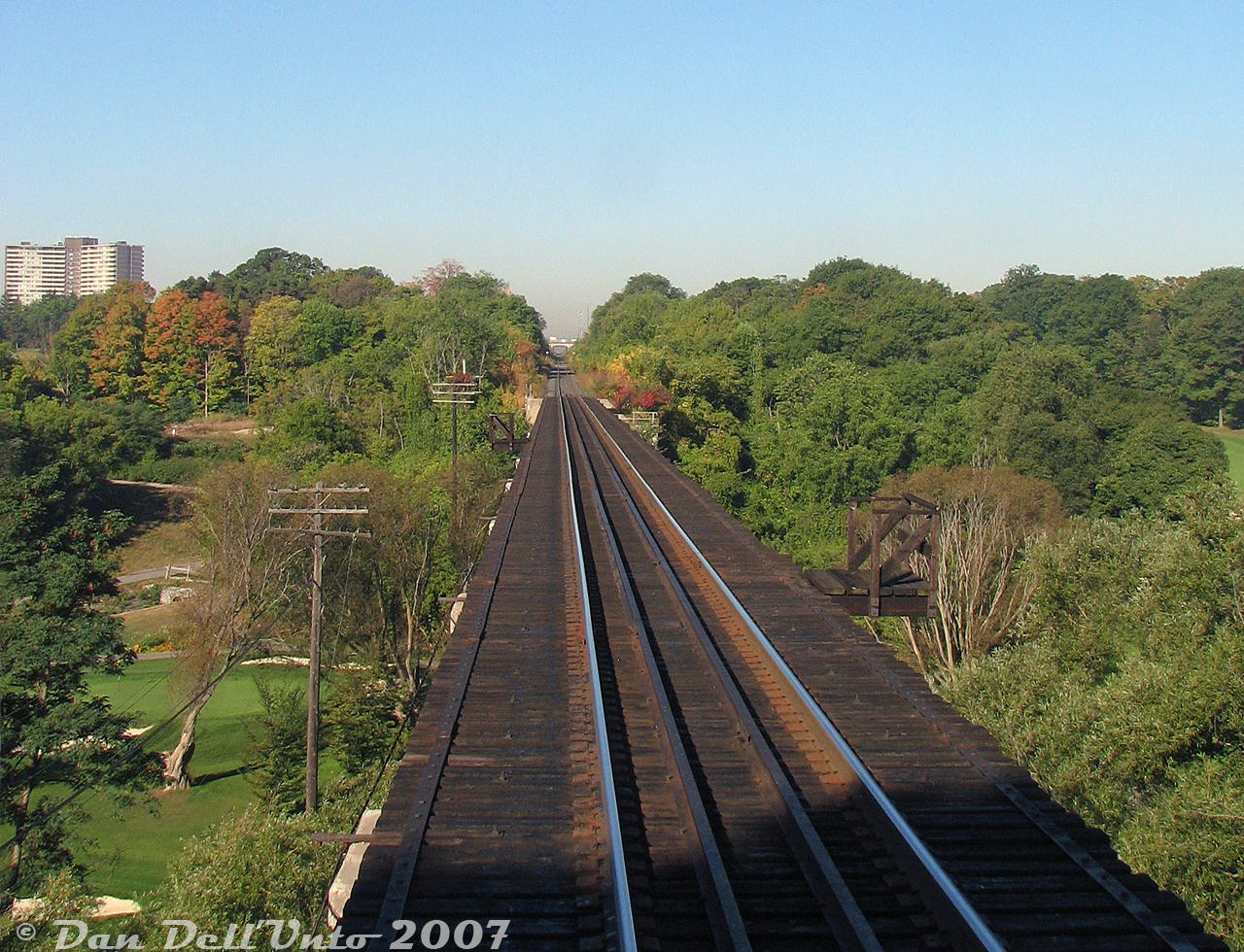 "It's 9:20am coming into the City of Toronto on a bright and sunny morning, and the traffic on Highway 401 in the distance is we don't care, because we're taking the GO train".

One of the more scenic spots along the Weston Sub is the old Grand Trunk Railway bridge crossing the Humber River, seen here out the rear of GO cab car 237 trailing train #252 into Toronto. Located just north of the town of Weston at "CN McGill", there's no shortage of lush green foliage in the area surrounding the river valley, part of which is home to the Weston Golf and Country Club's sprawling golf course on the floodplains below (see 1971 aerial here). Note the tall codeline/telegraph poles remaining alongside the bridge, and the lack of any handrails for safety (the small bridge platforms, relics from back in the day that used to hold fire barrels, remained for anyone brave or unsmart enough to cross on foot).

In the distance through the cut of trees, the line climbs up to Highway 401 overpass, Islington Avenue and Etobicoke North GO station at the top of the hill. The two signs in the distance warn trains of the private golf course crossing. This stretch had been known to cause problems in the fall due to leaves on the tracks stalling freight trains climbing the grade, like CN #577, sometimes resulting in lengthy delays and cancellations to GO service (like that one time with two GP40-2LW's that had to double their train in the pouring rain, SNAFU'ing evening rush hour service on the Georgetown line).

This section had remained single track for decades under GTR/CN until Metrolinx purchased the line in 2009, and proceeded to add three more tracks for expanded GO and new UPX service. Things here look a little bit different here today.