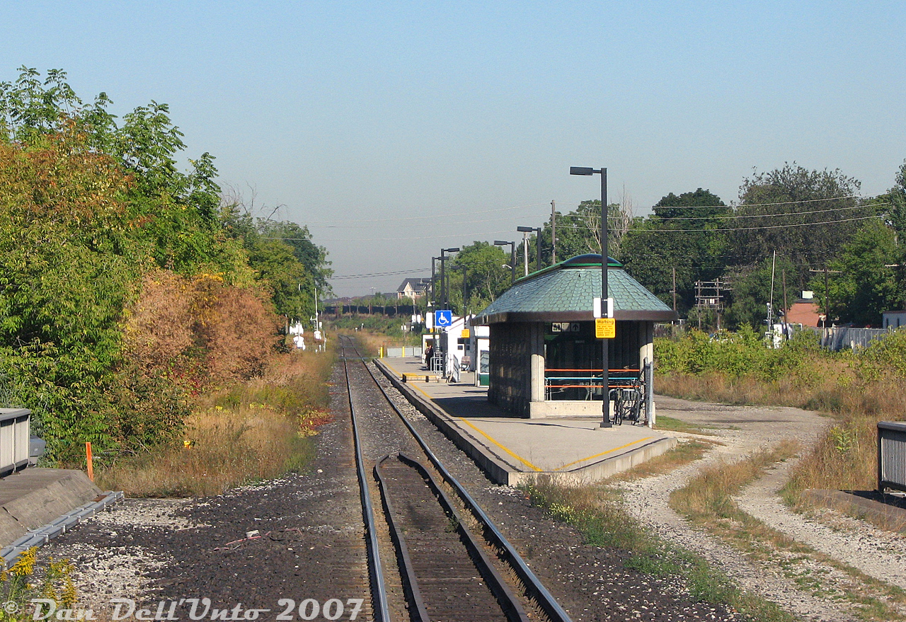 A nice view of the old Weston GO Station, very quiet and very quaint surrounded by lush greenery, until it was replaced by a brand new station to the south a few years later and subsequently obliterated by a giant grade-separation trench. The view today is from the rear of GO Transit cab car 237, departing on morning train #252 enroute to Union Station downtown. In the distance are the grade crossings for John, King, and Church Streets before the Weston Sub curved to the west and crossed the Humber River bridge at CN McGill.  This station was the original built by GO Transit for the launch of their new Georgetown line in April 1974, and replaced an old CN station that was previously here (demolished 1966). It did incorporate the old CN waiting room building that managed to survive. Like Bloor GO Station, the amenities here were also sparse, with some shelters, a small rectangular insta-station building, and an underground tunnel at this (south) end of the platform going under the tracks and coming out along the Lawrence Avenue underpass below (note bridge railings). The north end of the platform fronted onto John Street, where a very small GO parking lot was shoehorned in nearby almost as an after though. The odd platform shape at this end was for a CN service track that had previously run along the back of the station and connected to interchange tracks along CP's MacTier Sub on the right (incidentally, there was a CN-CP connecting track still present just to the south of here).  The demise of this incarnation of Weston Station came about with the idea for a new "Blue 22" Pearson airport express train (initially planned to use rebuilt RDC cars from IRSI) and expanded all-day two-way Georgetown corridor GO service with the West Toronto grade separation happening. Both would have required an updated, modernized station on site, although the UPX wasn't originally supposed to stop at Weston. The residents of Weston weren't happy about all of this, and launched a grassroots campaign targeting "Dalton's Dirty Diesels" (after then-Ontario premier Dalton McGuinty, more on him in a future post) due to all the extra diesel trains that would be running through the corridor on the expanded GO and new UPX lines. Among other things they wanted electric trains, a stop at Weston, and a grade separation for the about-to-be-busier rail corridor (that already intersected their neighbourhood for decades dating back to the steam era).  Only two of those three demands were met: they got their trench, and their UPX stop in the form of a new Weston station opened around 2012. There was lots of talk about electrification and pushing for studies, including planning to do the section of the corridor for the UPX line and a stretch from Union to Mimico so the UPX trains could be serviced, and possible servicing facilities at Humberview. The RDC idea was replaced with new Nippon Sharyo DMU trainsets with Tier 4 emissions diesel engines. This was also part of why GO sent an MP40 down to MPI for Tier 4 conversion into an MP54, as "Tier 4" and "clean diesel" were some of the PR-friendly terms thrown about to appease the residents (since all the studies and implementation of electrification wasn't practical or possible in the given timeline for many reasons). Ultimately nothing really became of it, as after the trench went in and the new efficient UPX service started up, the residents soon forgot about electrification and everything quieted down.  Someone else had the last laugh though: after all that work, CP's MacTier Sub was left fully at-grade next to the trench, forcing residents to keep waiting for long CP diesel freight trains to pass through.