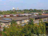 An overhead overview of CN's old Hamilton freight sheds, out of use for a number of years at the time of this photo, located adjacent to the CN/Southern Ontario Railway's Stuart Street Yard. The main offices were in the brick portion on the right, while the bulk of the building was warehouse space with truck loading docks. Four rail sidings (two on each side, some still visible) ran along both sides of this end of the building for spotting boxcars for loading/unloading. There was also a team track/ramp track in the foreground, obscured by all that brush.<br><br>According to the informative "Building GO Transit" article by Wilfred Sergeant, as part of the relocation of much of CN's freight yard operations in downtown Toronto, Mimico and Danforth to Vaughan in the 1960's (the new Toronto/MacMillan Yard), their downtown express and LCL operations were to be consolidated from their old Simcoe Street LCL freight sheds (along Front Street, near CP's own sheds) and the express building adjacent to Union Station into a new, modern, larger express-freight facility located within the new yard up in Vaughan (known as Maple). This was due to a study at the time that found many shippers were moving their operations out of the downtown area to new industrial areas and business parks being developed in the suburbs along Highway 7.<br><br>The new Maple express/freight shed was also to feature new modern automated sorting processes and equipment. In order to test and refine this, a smaller test shed was built here in Hamilton and outfitted to test and refine the new technology and processes that were to be implemented in Maple. It replaced some of the older local freight/express facilities CN had in the area.<br><br>As per other notes and photos by Doug Page, the Hamilton shed was <a href=http://www.railpictures.ca/?attachment_id=39425><b>built in 1964-65</b></a> (on the site of the <a href=http://www.railpictures.ca/?attachment_id=39179><b>old CN Hamilton roundhouse</b></a>), and closed in 1997. By the time of this photo in 2007 it was vacant, and two years later in 2009 it would succumb to the wrecking ball.