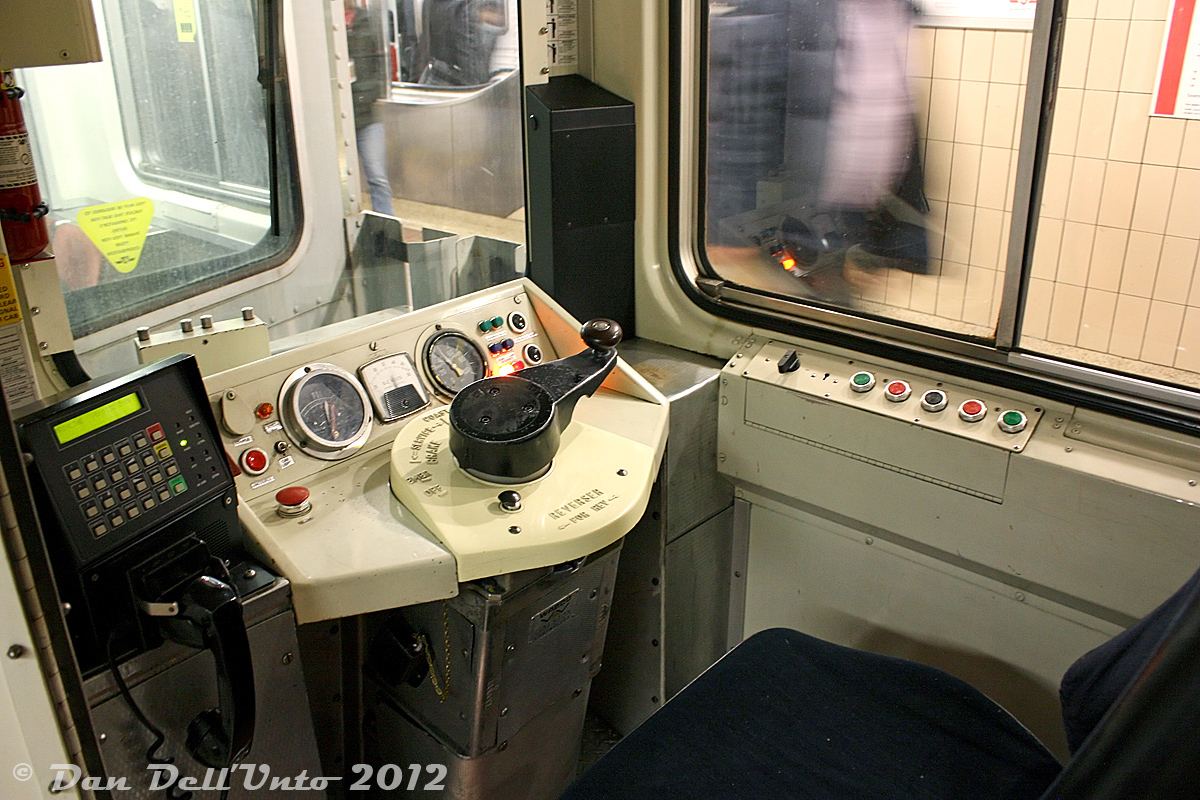 There's a lot of photos of TTC T1 and TR cabs floating around, but not many of the old Hawker Siddeley H5's, so here's a cab-view of TTC H5 5759 during a quick rush-hour pause at Union Subway Station while it was in service as the guard car. All the important bits are here, including speed and air pressure gauges, DC ammeter, indicator lights, a big red button (don't push!) for the horn, a smaller red button to uncouple the car (don't touch!), the communications unit, a seat (don't sit!), the manually-cranked run number box mounted in the front window, the right side door control panel with door opening and closing buttons (don't press!), and the large WABCO controller arm that needs to be pushed down (as a deadman feature) and rotated to the correct throttle setting for operation. The CN/VIA Turbo Trains used a similar throttle arrangement, as did the MLW/Bombardier LRC demonstrator JV1, and the HSC-built Montreal Expo Express trains. The reverser lever can be seen mounted on the gold chain in the pouch below (it would be inserted in the slot below the main panel if the car was leading)

All the old now-retired Hawker/UTDC equipment used the same basic controller setup, but by the T1's they switched to a T-style controller lever that carried over to the TR's.

There's some good in-cab footage of an H1 operating in the 1998 TV-movie version of "The Taking of Pelham 1-2-3" filmed in Toronto using an old H1 subway car, and featuring a surprisingly notable cast including Vincent D'Onofrio, Lorraine Bracco, and Richard Schiff.