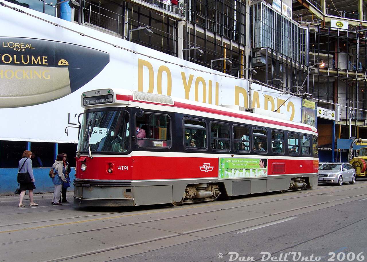 The north-east corner of Yonge and Dundas has traditionally been a magnet for shooting streetcars over the years, both due to its proximity to the Eaton Centre, the busy Yonge-Dundas Square tourist destination, and being a transfer point to/from the Dundas Subway Station on the Yonge line just below.Here's the 2006 view of what the location looked like: TTC CLRV 4174 on the 505 Dundas loads passengers in front of the large blue construction hoarding that had been erected along the NE corner where the old Brown Derby Tavern building once was (it had been renovated to house various commercial shops in the 70's). It was demolished a few years earlier for a new grand commercial development known at the time as "Metropolis", since renamed "10 Dundas East" and now "The Tenor".The eastern potion was built over and around the old Ryerson University parking garage and bookstore. The university green-lit the development over their property in exchange for being allowed to use the movie theatres inside the AMC theatre as lecture halls for holding classes during the afternoons and off-peak hours. Just flash your handy-dandy Ryerson ID to get in, but the fun ended there as there weren't any movies playing during the off-hours. Some shops started opening during 2007 when most of the building was nearing completion.

Another sign of the times: this view pre-dates any Google Streetview images showing the construction and big blue hoarding.