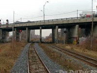 After departing our final station stop before downtown Toronto, we're picking up speed on the jointed rail stretch of the Weston Sub between <a href=https://www.railpictures.ca/?attachment_id=59667><b>Bloor GO</b></a> (in the distance) and <a href=https://www.railpictures.ca/?attachment_id=59695><b>CN Parkdale</b></a> on the home stretch to <a href=https://www.railpictures.ca/?attachment_id=59467><b>Union Station</b></a>, zipping under the <a href=http://www.railpictures.ca/?attachment_id=39238><b>Dundas Street West overpass</b></a> on the way out of West Toronto. The northbound advance signals to the diamond at West Toronto are visible on this side of the bridge, that was undergoing some rehabilitation work at the time (including new railings recently installed).<br><br>We're on the south (west) track of the double track CN Weston Sub. The tracks on the left are the double track CP Galt Sub running parallel down the rail corridor, this location being known as CP Dundas in employee timetables. On the right, CP's old TG&B "Bruce Service Track" (now removed) once used to duck under the bridge and go to the Compressed Metals scrapyard just south of Dundas. The track continued out the other side as a CN siding off the Newmarket Sub (see middle of 1971 aerial <a href=https://www.toronto.ca/ext/archives/s0012/fl1971/s0012_fl1971_it0046.jpg><b>here</b></a>). On the north side of the bridge to the right is the Nestle chocolate factory, once home to Rowantree Chocolates, off Sterling Road (apparently sugar from Redpath downtown was shipped here via hoppers). Just a stone's throw away, the Newmarket Sub ducked under Dundas below <a href=http://www.railpictures.ca/?attachment_id=44939><b>its own bridge</b></a>.<br><br>To the left in the distance are the two towers of <a href=http://www.railpictures.ca/?attachment_id=59668><b>The Crossways Mall</b></a> at <a href=http://www.railpictures.ca/?attachment_id=53600><b>Bloor and Dundas</b></a>.
