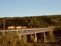 Northward from Prince George, the British Columbia Railway crossed the Fraser River one last time to reach Bridge yard serving pulp mills and onwards to Peace River country.  On Friday 1976-09-17 at1825 PDT, that bridge was utilized by a northward train of empties, powered by BCOL 643 + 806 (ex Erie Lackawanna 2456) and PGE 576 not yet repainted.
