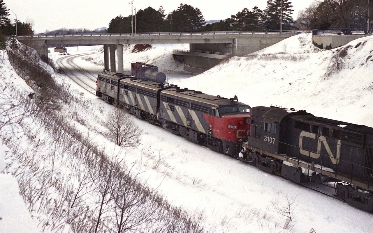 Another one of those typical blah winter days, but I found the desire to get out trackside anyway. From the hillside at the Junction I caught a going-away shot of VIA' #75 which I grabbed because I didn't know CN 3107 was fourth unit until the train was going by. Power is all still in CN colours: 6786, 6860, 6767 & 3107. What is interesting is a couple of MoW cars on the old steam helper track, now just a spur. I do not ever recall cars being pushed so far up toward the end of track.
This is the York Blvd bridge, and the train is approaching Ham West. The RR structure in the top upper left was torn down not long after this shot was taken.