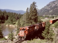 Eastward woodchip loads from Midway and Grand Forks sawmills bound for Kraft pulp mill near Castlegar dominate on an extra east with CP 3021 + 4211 + 8816 + 5023 (GP38-2, C-424, GP9, and GP35) crossing the Kettle River at mileage 82.7 approaching Cascade on Saturday 1984-06-16.  Another 1.6 miles east is another (and much bigger) bridge, the fifth of total five over the Kettle River, then the beginning of a significant ascent to the summit at Paulson Gap and Farron.

<p>Today, this is the Columbia and Western Rail Trail.
