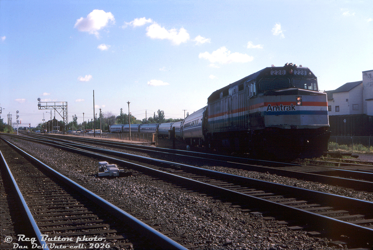 Here's a neat one from Reg: unconventional loading at the VIA/CN Burlington Station at Burlington West. For some reason the mainline tracks couldn't be used (might have something to do with the track workers by the station in the distance), so the morning VIA-Amtrak "Maple Leaf" from Toronto to the states has to make a minor reroute around the station and load on the back track. Seen here paused for its station stop is Amtrak F40PH 228 leading seven Amfleet cars, sitting at an odd angle, with passengers loading by the last car. Anyone know the incident?

Reg Button photo, Dan Dell'Unto collection slide.