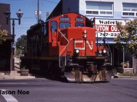The CN 15:30 Kitchener Job with GP9RM 7030 makes a mid-afternoon appearance in downtown Waterloo, as the crews heads to the town of Elmira, Ontario on the Waterloo Spur light power. Often during the month of July in the 90’s, with the Budd Plant in Kitchener slowing production for summer shut down, they didn’t require CN service daily, so the 15:30 Job would head to Elmira earlier in the afternoon rather than later in the evening.



