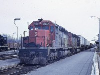 Two of CN's first three SD40s, 5002 and 5000, lead train 301 down the main line at Capreol, Ontario under the watchful eyes of a CN Police officer.  SW1200 7033 sits on spot on track 2R.