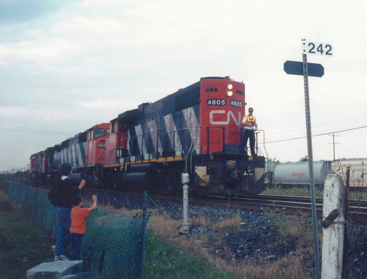 Once I learned of Brighton's most infamous railfanning spot  (click here from my first trip the summer before to Memory Junction)  I started to make a few stops whenever I headed east to go camping deep in the heart of Prince Edward County. This night, again proved to be eventful. I'm not sure of the circumstances, but CN 4805, 5504 and two other unidentified units were backing up to their train. They proceeded east about half hour of snapping this photo. 


The conductor gets a friendly wave from a father and son, as they head back to their train. That's the purpose of Ralph Bangays vision, I think. Making memories, watching trains. Doesn't get any better than this, does it?