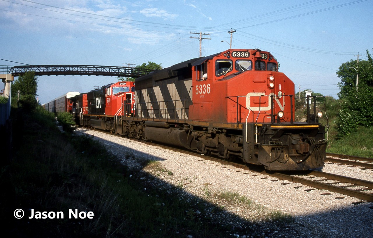 CN train 395 is viewed slowly rolling down the siding in Kitchener, Ontario to clear the mainline for VIA #89, which was due within the hour. Powering the Chicago-bound freight were SD40-2(W) 5336, SD75I 5629 and SD40-2(W) 5360. This was likely brand new 5629’s first trip down the line as it was released from the GMDD plant in London just over a week prior on June 2, 1996. Once the crew reached the yard, they would lift the loaded Budd automotive frame cars and await the arrival of 89 before proceeding west. In the meantime, the friendly conductor invited several local railfans up to tour the cab of fresh 5629 to get some photos. What great times they were.