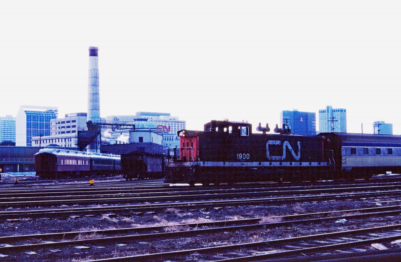 Prior to the construction of VIA's Winnipeg Maintenance Centre in the late 1980s, passenger cars were kept in the East Yard and moved up to station by the "depot" switcher (a GMD1 in the winter and an SW8/SW900--or occasionally an SW1200RS--in the summer). On a cloudy March afternoon in 1982, CN 1900 moves a VIA/ex-CP stainless steel car through the yard. Off to the left you can see the passenger cars for the Prairie Dog Central steam train which operated on Sundays in the summer from CN's St. James to Grosse Isle. Behind the coaches, the Rivers Sub freight tracks bypassing the station can be seen. Today there are also several hoppers of coal for the steam heating facility which supplied the station (note smoke stack and the dome complete with a red CN logo). Of course, today this is The Forks market.