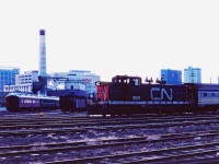 Prior to the construction of VIA's Winnipeg Maintenance Centre in the late 1980s, passenger cars were kept in the East Yard and moved up to station by the "depot" switcher (a GMD1 in the winter and an SW8/SW900--or occasionally an SW1200RS--in the summer). On a cloudy March afternoon in 1982, CN 1900 moves a VIA/ex-CP stainless steel car through the yard. Off to the left you can see the passenger cars for the Prairie Dog Central steam train which operated on Sundays in the summer from CN's St. James to Grosse Isle. Behind the coaches, the Rivers Sub freight tracks bypassing the station can be seen. Today there are also several hoppers of coal for the steam heating facility which supplied the station (note smoke stack and the dome complete with a red CN logo). Of course, today this is The Forks market.