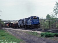 Some all-blue Conrail action on the CN Oakville Sub: CR GP38 7810, U23B 2781 and GP38-2 8090 roll an unknown eastbound through Aldershot. There appears to be some heavy equipment loaded on the head end flatcars, possibly Massey Ferguson farm equipment loads.<br><br><i>Bill McArthur photo, Dan Dell'Unto collection slide</i>.