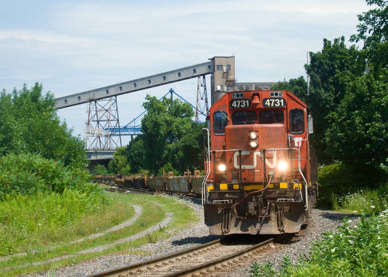 CN 4731 (still sporting a real bell) leads a transfer out of the Port of Montreal, with bad ordered well cars up front. They will be repaired at the nearby Pointe St-Charles Yard and then return to the port.