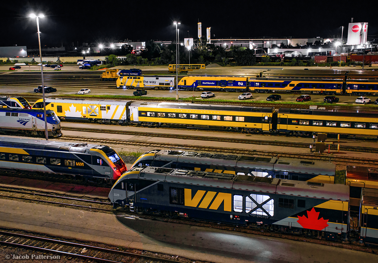 The early morning hours at VIA's Toronto Maintenance Centre find numerous pieces of equipment at the ready for upcoming departures to Ottawa, Montreal, Windsor, and New York.  The new Siemens Charger sets make up the majority of the scene, including "LUMI" at centre, with stored Budd equipment in the distance beyond the newest delivery or Siemens equipment.  Ontario Northland's third and final set of equipment, ONT has just been delivered by and is seen being positioned by VIA 903 after a brief stop at the fuel pad.  Note freight equipment from CN L543 in the distance, waiting for the pair of geeps to turn on the wye before returning to Oakville.