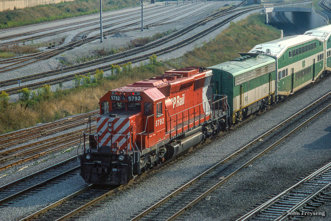 Shoving on the rear of a special shuttle train, CP SD40-2 5792 carries the markers on the west end of a set of GO bilevel coaches passing beneath Bathurst Street on approach to Union Station.  GO GP40TC 726 leads on the east end.  In September 1984, Pope John Paul II celebrated an outdoor mass in Downsview Park before an estimated 400,000 people. No car parking was allowed for the general public on or near Downsview Park, everyone attending was encouraged to take the TTC subway to Downsview and use shuttle bus/walk to the site of the mass. In addition to the above, GO ran a large number of extra trains on the Lakeshore Corridor to bring the Downsview Mass attendees to the Union Station where they would transfer to the University Line subway to Downsview, TTC running a rush hour schedule.  The pictured equipment would run up the Newmarket Sub to Rutherford Rd GO Station before proceeding to the makeshift platform built at the De Havilland air craft plant near Downsview to shuttle people who parked their cars at Rutherford GO to the mass.

GO Transit also borrowed CN power on this day.

Scan and editing by Jacob Patterson.