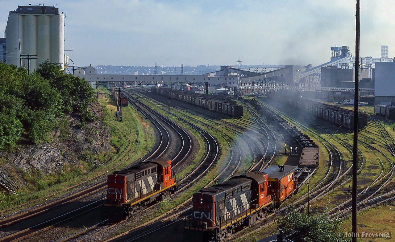 Looking east from the Young Avenue bridge, CN MLW RSC17 1776 works a cut of container flats in Halifax yard, while RS18 3660 sits off to the left.  Note the string of Bombardier locomotives, possibly in storage, at upper left.

Scan and editing by Jacob Patterson.