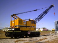 <b> An American arrives in town </b> <br>
In 2003, QIT (Riviere Romaine Railway) replaced their aging Ohio locomotive crane with a remanufactured American model 855 DEH (Diesel Electric traction, Hydraulic swing) crane. <br>
It is seen here on July 2, 2003 outside their equipment shop during in-service commissioning. <br>
In the background you can see locomotive QIT 1 (ex-QIT 4) on static display at the roadside leading into town. Directly across the street from the Hotel Du Havre which was my home for the week. <br>